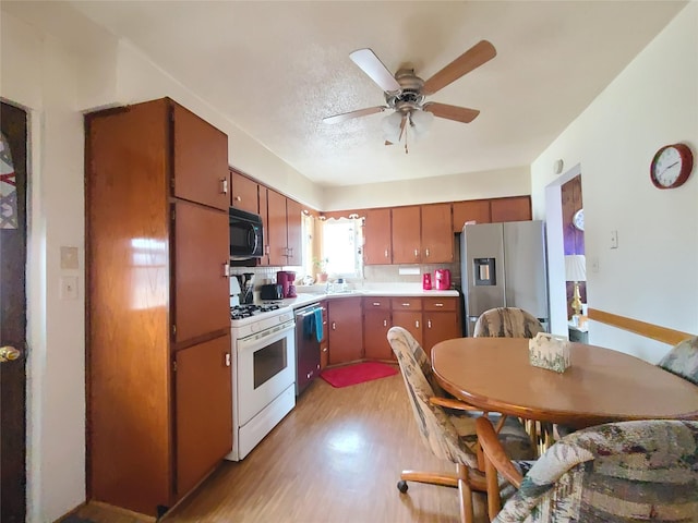 kitchen featuring sink, a textured ceiling, light wood-type flooring, ceiling fan, and stainless steel appliances