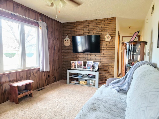 living room featuring carpet flooring, a healthy amount of sunlight, wooden walls, and a textured ceiling