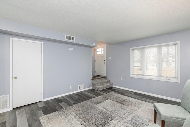 interior space with a textured ceiling and dark hardwood / wood-style flooring