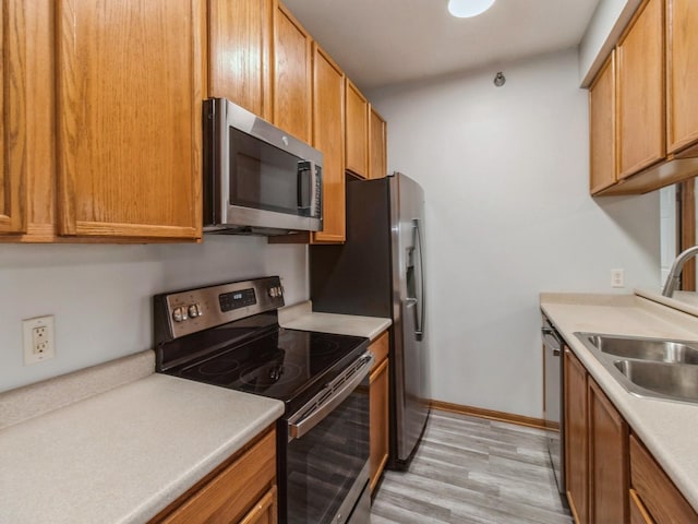 kitchen featuring stainless steel appliances, sink, and light hardwood / wood-style floors