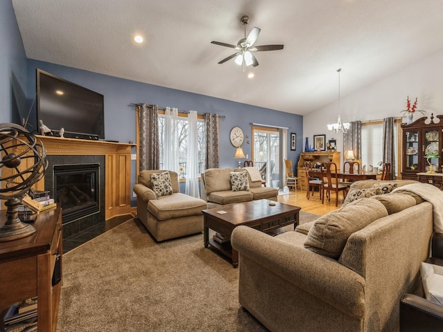 living room featuring a tiled fireplace, ceiling fan with notable chandelier, and vaulted ceiling