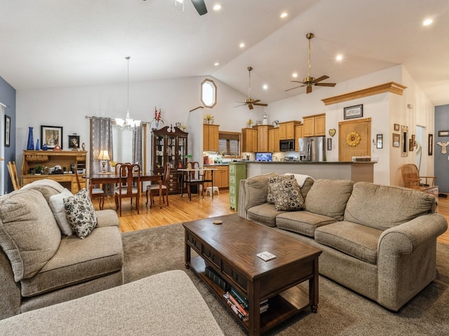 living room featuring high vaulted ceiling, ceiling fan with notable chandelier, and light hardwood / wood-style floors