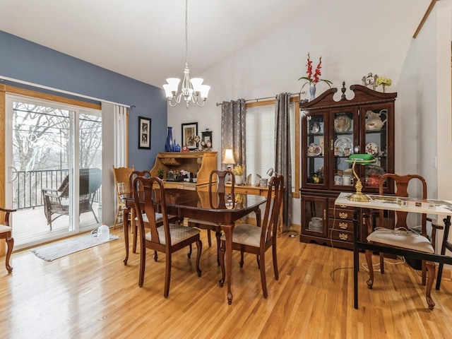 dining area with lofted ceiling, a notable chandelier, and light hardwood / wood-style floors