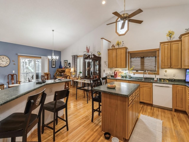 kitchen with pendant lighting, sink, dishwasher, a kitchen bar, and a kitchen island