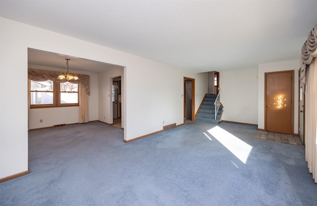 carpeted spare room featuring a chandelier