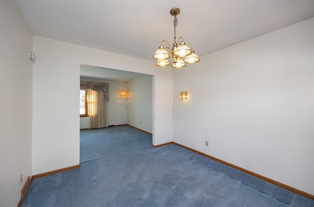 carpeted spare room with a chandelier