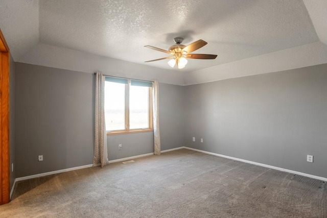 empty room featuring a textured ceiling, a raised ceiling, ceiling fan, and carpet