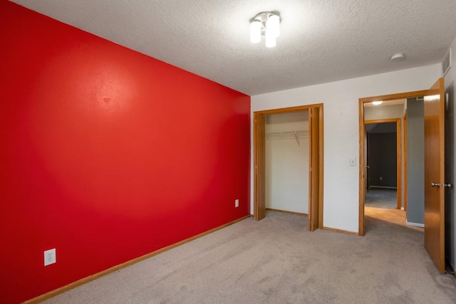 unfurnished bedroom featuring light colored carpet, a textured ceiling, and a closet