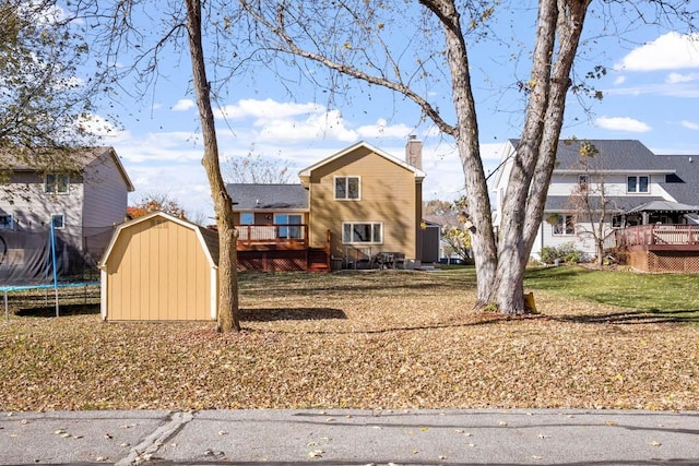 front facade featuring a front lawn, a deck, a trampoline, and a storage shed