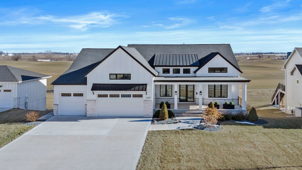 modern farmhouse with covered porch and a front lawn