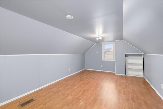 additional living space with vaulted ceiling and light wood-type flooring