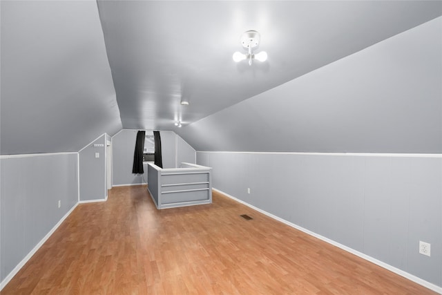 additional living space with vaulted ceiling and light wood-type flooring