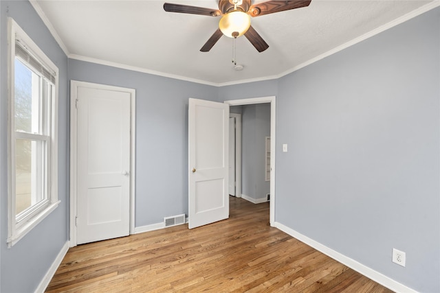 unfurnished bedroom featuring ceiling fan, ornamental molding, and light wood-type flooring