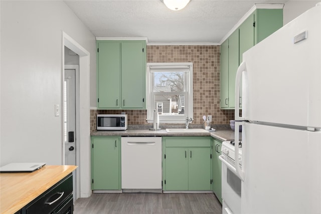 kitchen with sink, white appliances, backsplash, and green cabinets