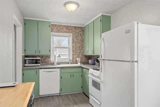 kitchen with tasteful backsplash, sink, green cabinets, and white appliances