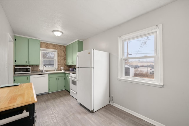 kitchen with backsplash, white appliances, light hardwood / wood-style floors, green cabinetry, and a textured ceiling