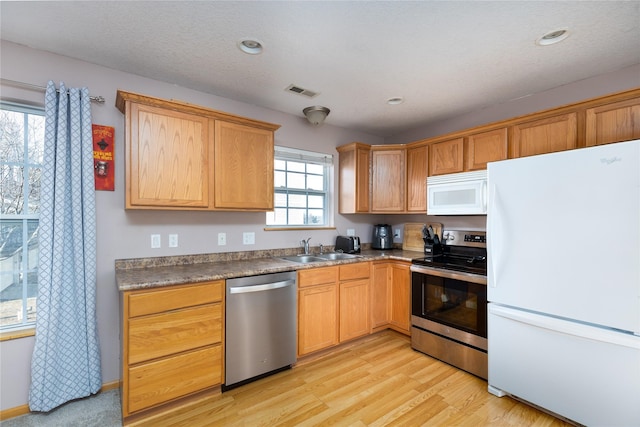 kitchen featuring stainless steel appliances, sink, light hardwood / wood-style flooring, and a textured ceiling