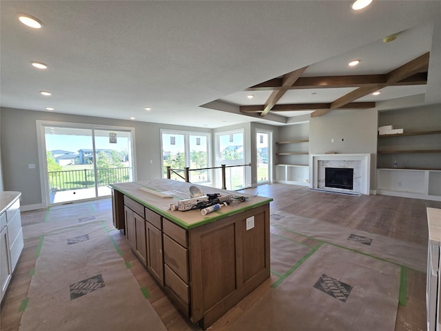 16207 Goodman Dr, Urbandale, IA 50323 - kitchen featuring recessed lighting, built in shelves, a kitchen island, beam ceiling, and light countertops