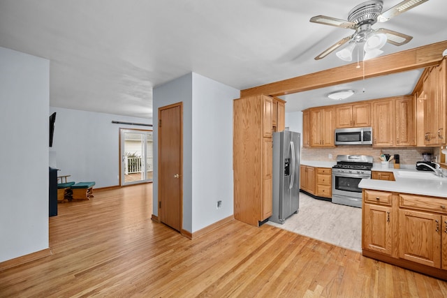 kitchen featuring sink, light wood-type flooring, ceiling fan, stainless steel appliances, and backsplash