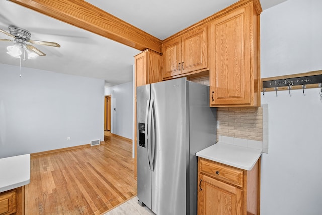 kitchen with beamed ceiling, stainless steel fridge, decorative backsplash, ceiling fan, and light hardwood / wood-style flooring