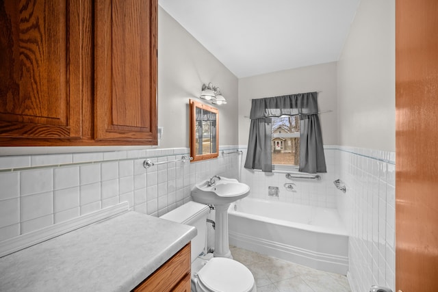 bathroom with sink, tile patterned flooring, tile walls, a bathing tub, and toilet