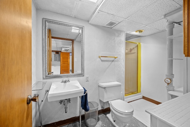 bathroom featuring a drop ceiling, sink, a shower with shower door, and toilet