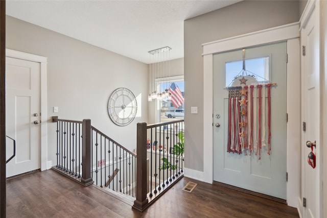 entryway with dark hardwood / wood-style flooring and a notable chandelier