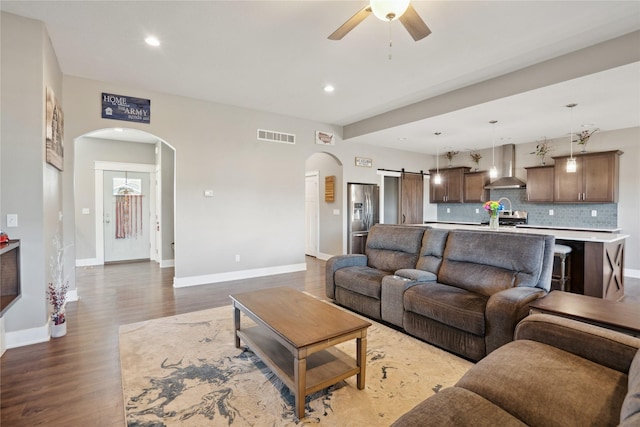 living room featuring wood-type flooring, a barn door, and ceiling fan