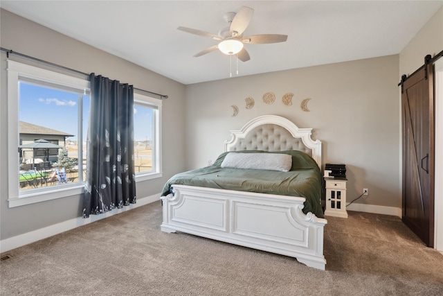 carpeted bedroom with a barn door and ceiling fan