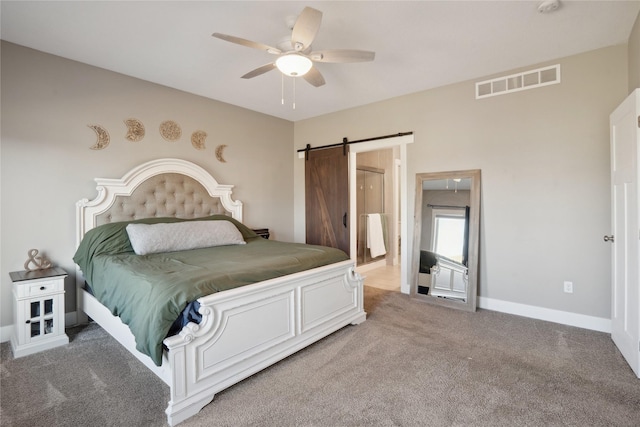 bedroom featuring a barn door, carpet, connected bathroom, and ceiling fan