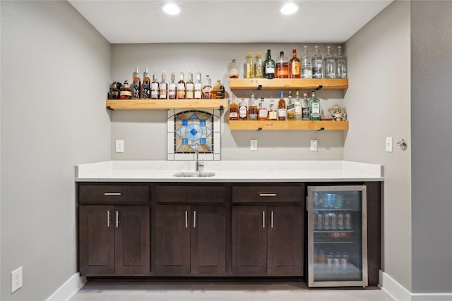 bar featuring wine cooler, sink, and dark brown cabinetry