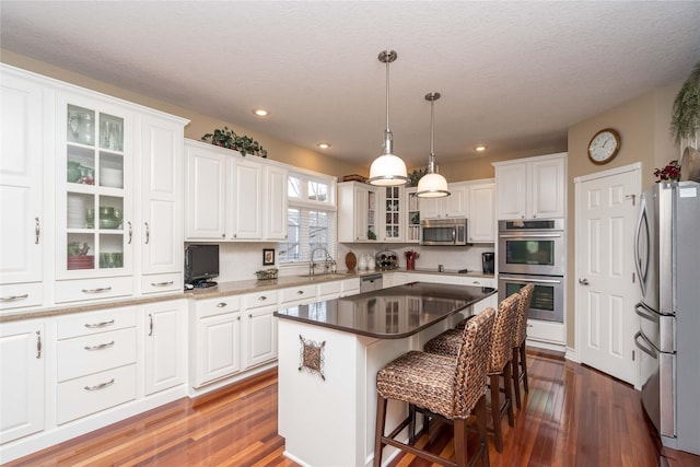 kitchen featuring white cabinetry, appliances with stainless steel finishes, a center island, and sink