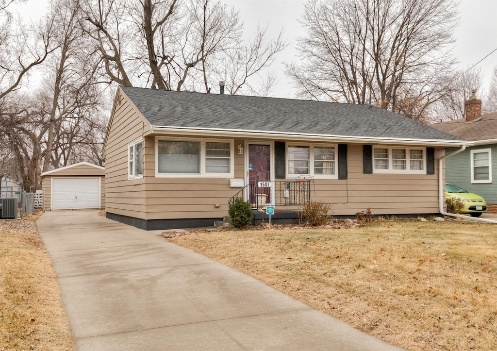 view of front of home featuring a front lawn, a garage, an outdoor structure, and central AC