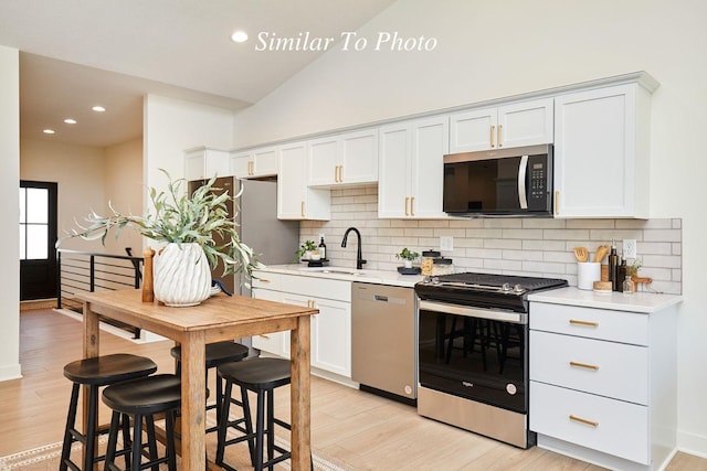 kitchen with a sink, light countertops, light wood finished floors, and stainless steel appliances