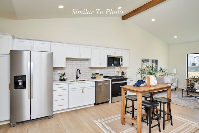 kitchen with light wood-style flooring, a sink, light countertops, appliances with stainless steel finishes, and backsplash