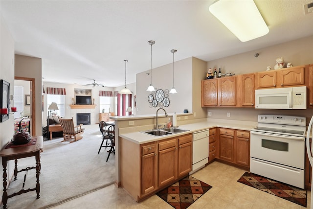 kitchen with sink, white appliances, hanging light fixtures, kitchen peninsula, and light colored carpet