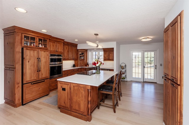 kitchen featuring pendant lighting, paneled refrigerator, a center island, and light hardwood / wood-style floors