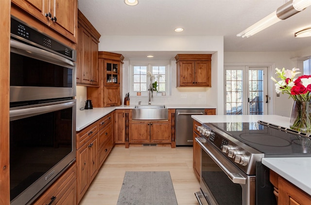 kitchen with stainless steel appliances, light hardwood / wood-style floors, sink, and a wealth of natural light