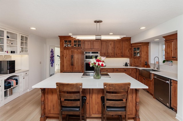 kitchen with sink, a breakfast bar area, stainless steel appliances, a center island, and decorative light fixtures