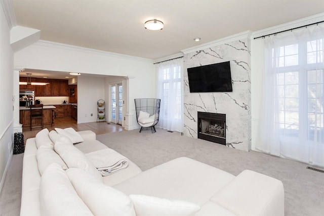 living room featuring light colored carpet, ornamental molding, and a premium fireplace