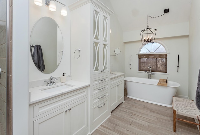 bathroom featuring vanity, hardwood / wood-style floors, lofted ceiling, and a bathing tub