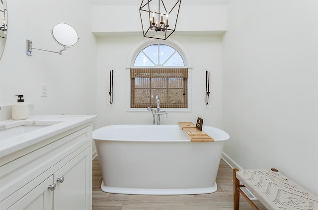 bathroom with hardwood / wood-style flooring, vanity, a bath, and a notable chandelier