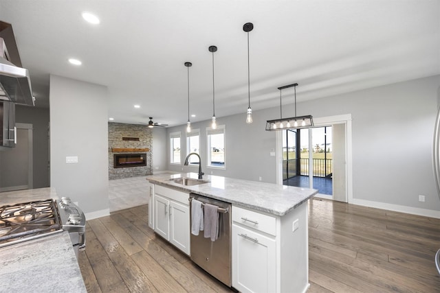 kitchen with appliances with stainless steel finishes, pendant lighting, sink, white cabinets, and a kitchen island with sink