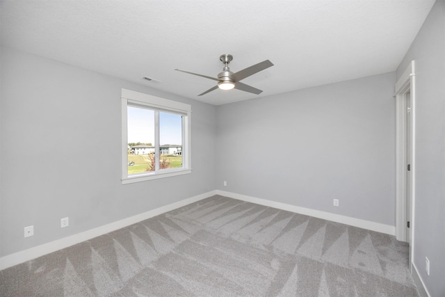 spare room with light colored carpet, a textured ceiling, and ceiling fan