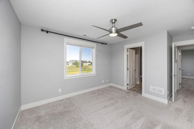 unfurnished bedroom with ceiling fan, light colored carpet, and a textured ceiling