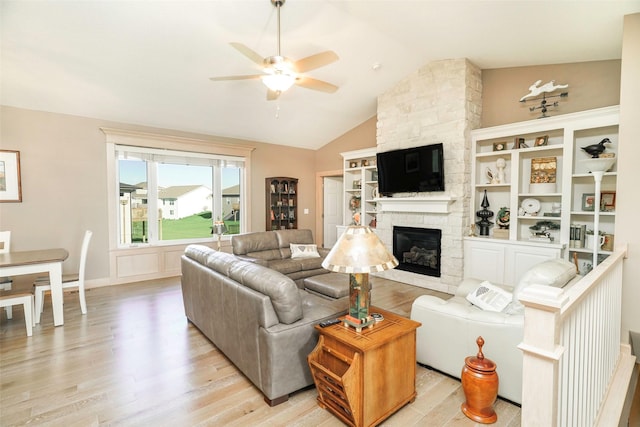 living room featuring ceiling fan, lofted ceiling, a fireplace, and light wood-type flooring