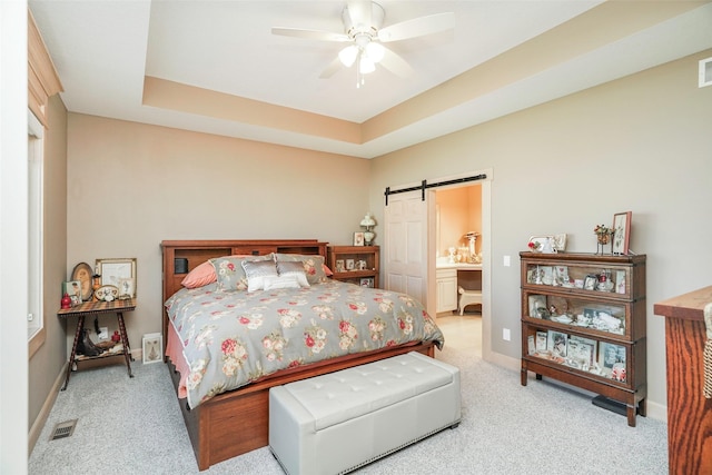 bedroom featuring a barn door, a raised ceiling, and light carpet