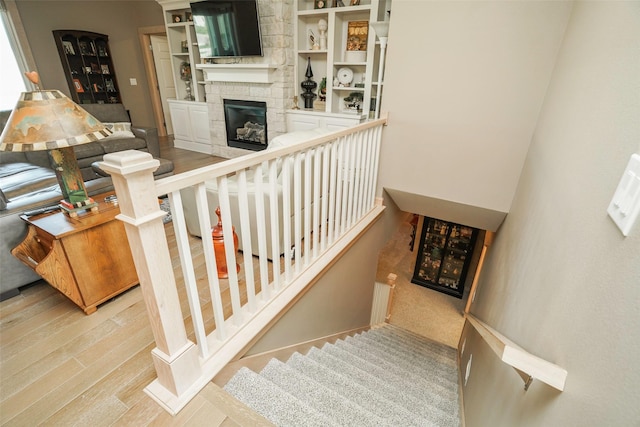 staircase with hardwood / wood-style floors and a fireplace