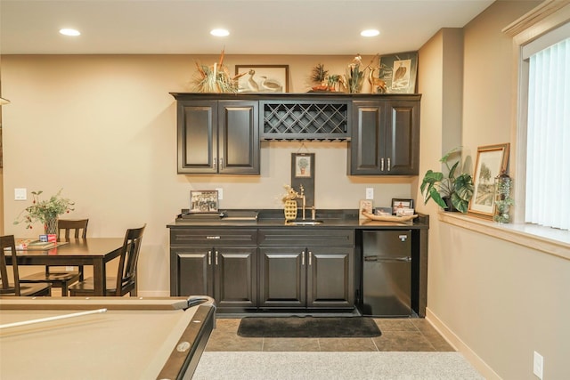 bar with black refrigerator, sink, and light tile patterned flooring