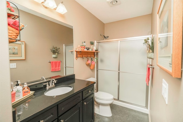 bathroom featuring tile patterned floors, vanity, toilet, and a shower with shower door